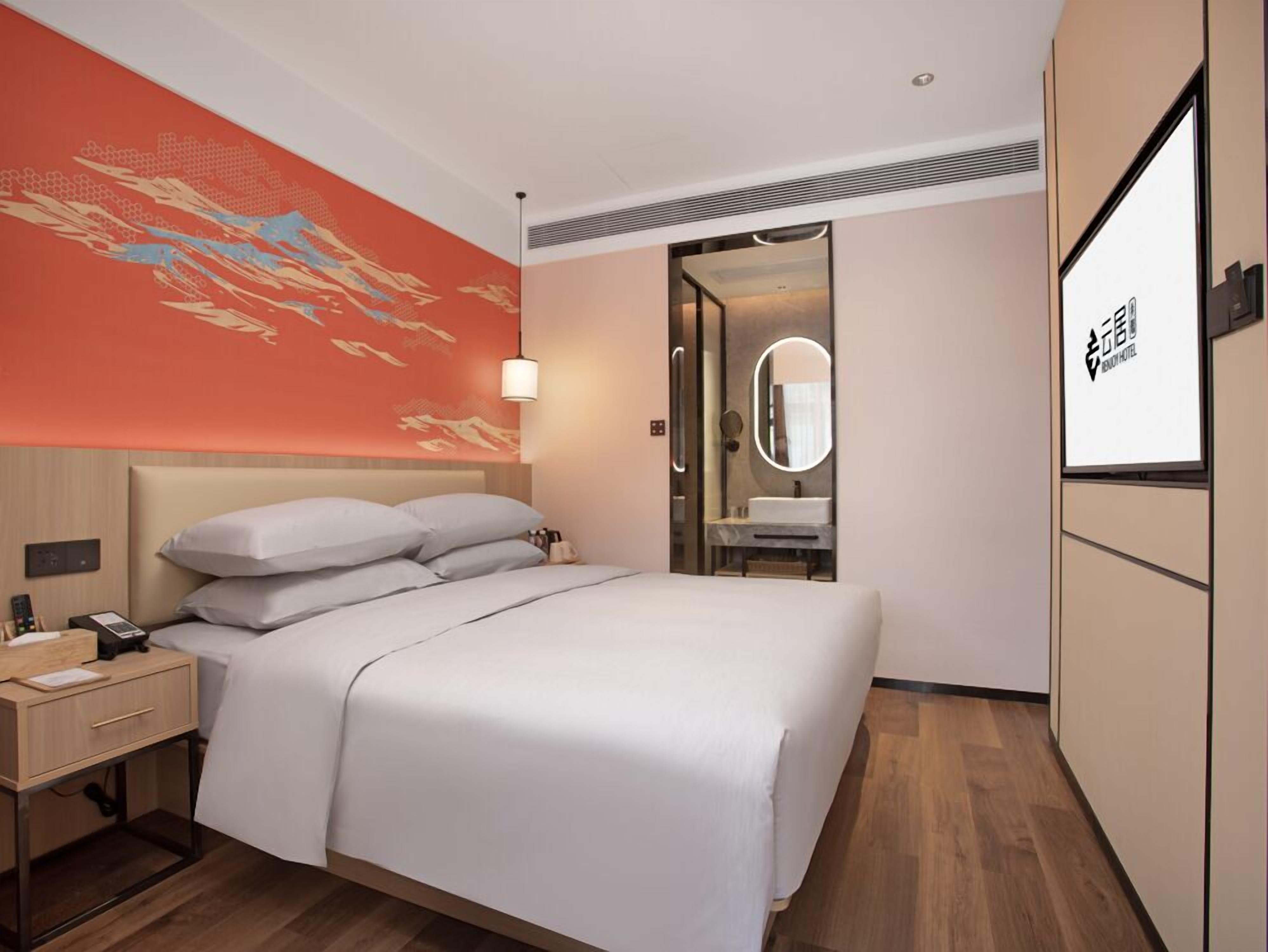 Una camera d'albergo con un letto, un comodino e un grande specchio.