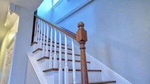 Una scala con balaustre bianche e ringhiere in legno.