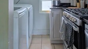 Una cucina compatta con mobili bianchi, un fornello e una finestra.