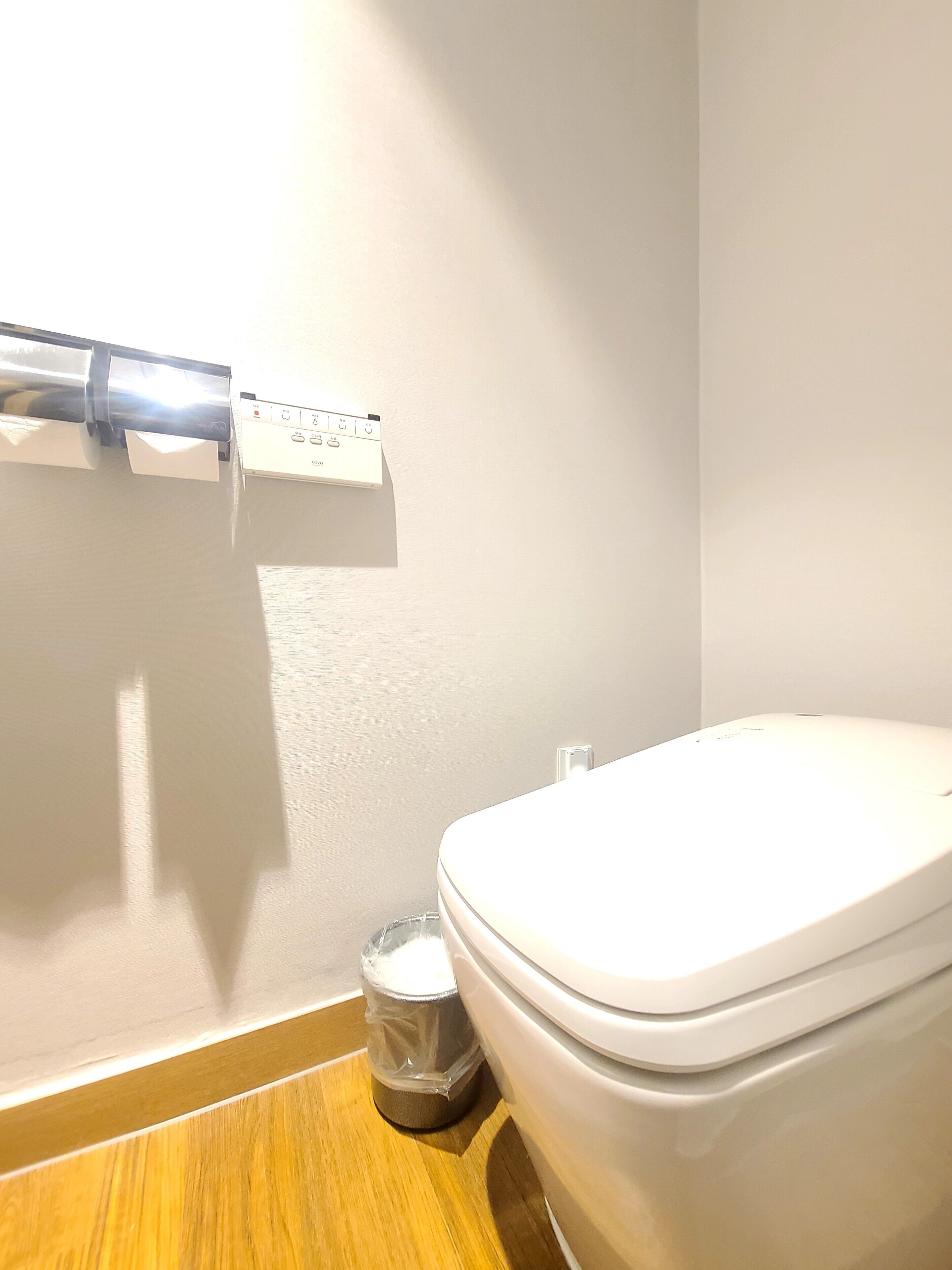 Une salle de bain équipée de toilettes, d’une poubelle et d’un distributeur d’essuie-tout fixé au mur.