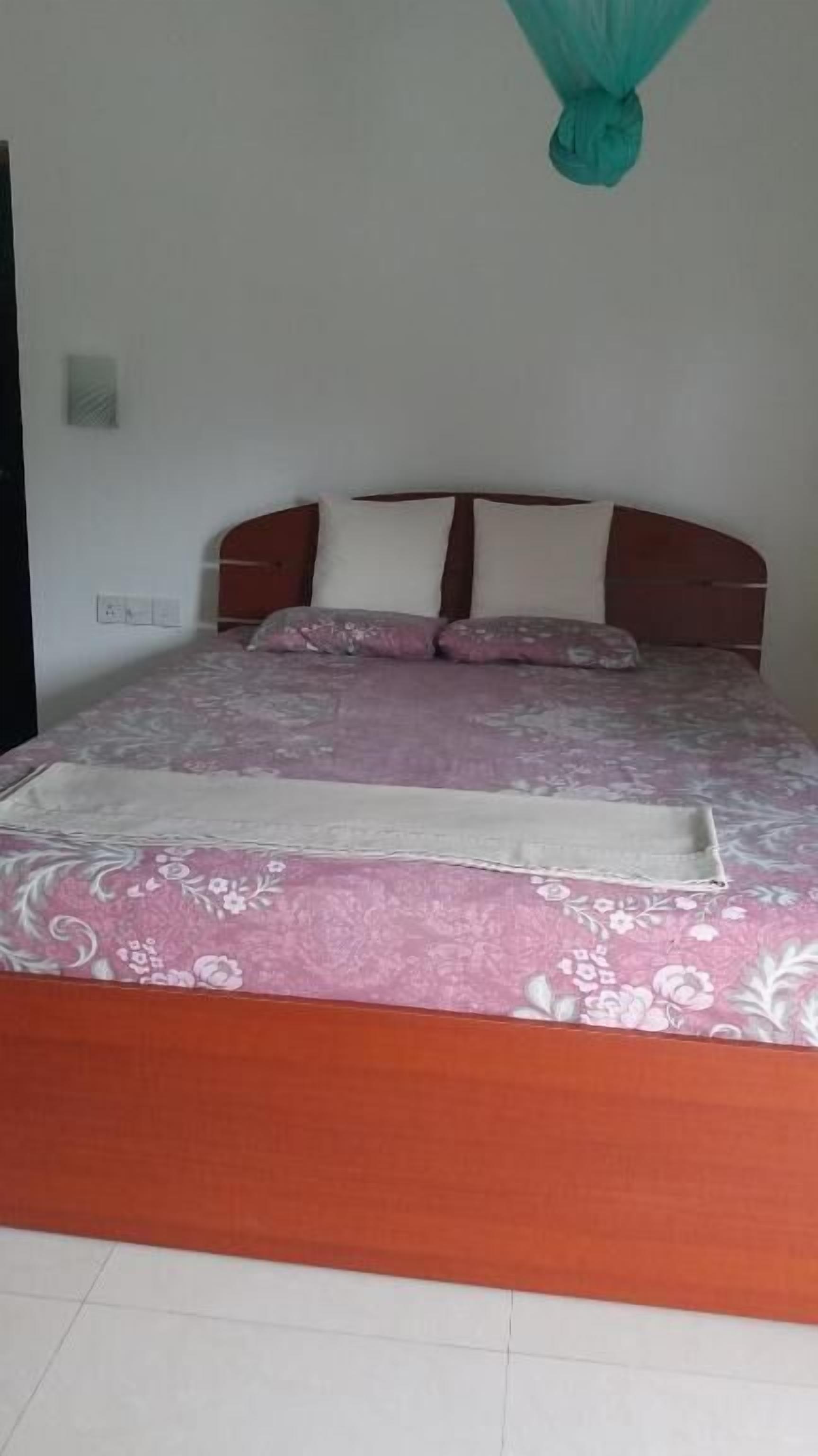 A bed with a floral bedspread, a wooden headboard, and a mosquito net.