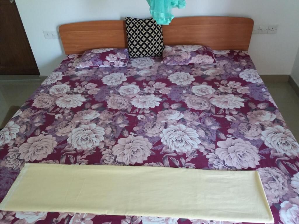 Una cama con colcha estampada, cabecera de madera y almohada con diseño.