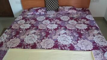 Una cama con colcha estampada, cabecera de madera y almohada con diseño.
