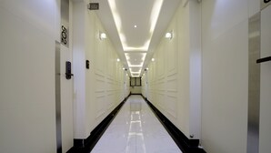 A long, narrow hallway with a reflective white floor and black borders, leading to a door marked with the number 502. - G&G Hotel (Ulsan)