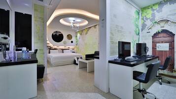 A modern hotel room with a bed, desk, and computer setup.