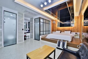 A modern hotel room with a large bed, a massage chair, a small table, and a large mirror reflecting the room. - G&G Hotel (Ulsan)