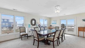 A spacious dining room with a large table and chairs, large windows, and a view of the beach. - 7019- Sara's Sea Breeze - Oceanfront Rodanthe | Hot Tub | Sleeps 12 (Rodanthe)