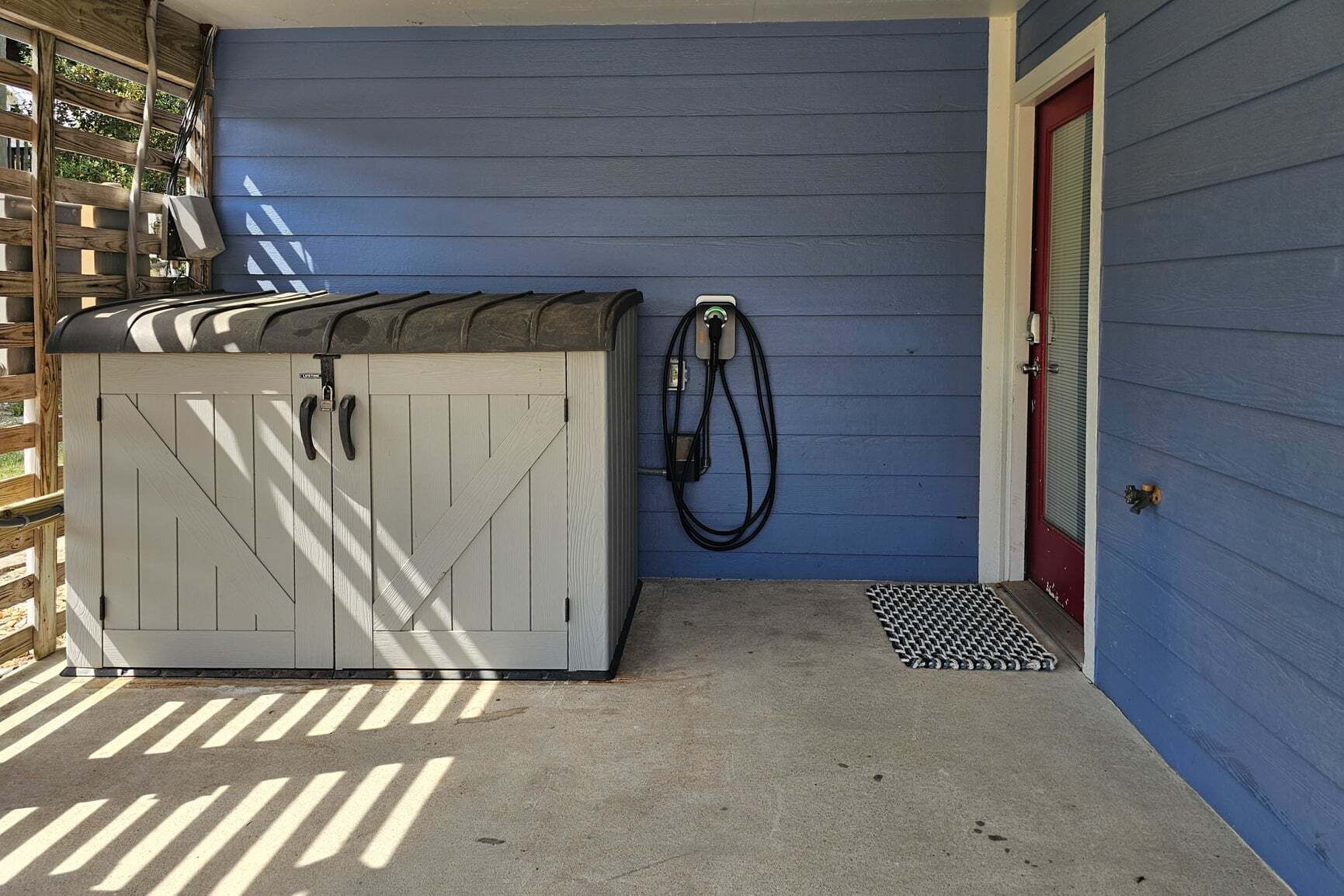 A covered outdoor area with a hot tub, a hose, and a door.
