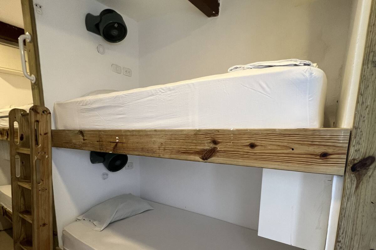 Ein Stockbett mit Holzbettrahmen und weißer Bettwäsche.