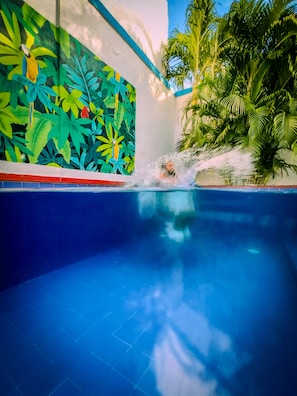 Ein Schwimmbad mit tropischem Wandbild und Palmen.
