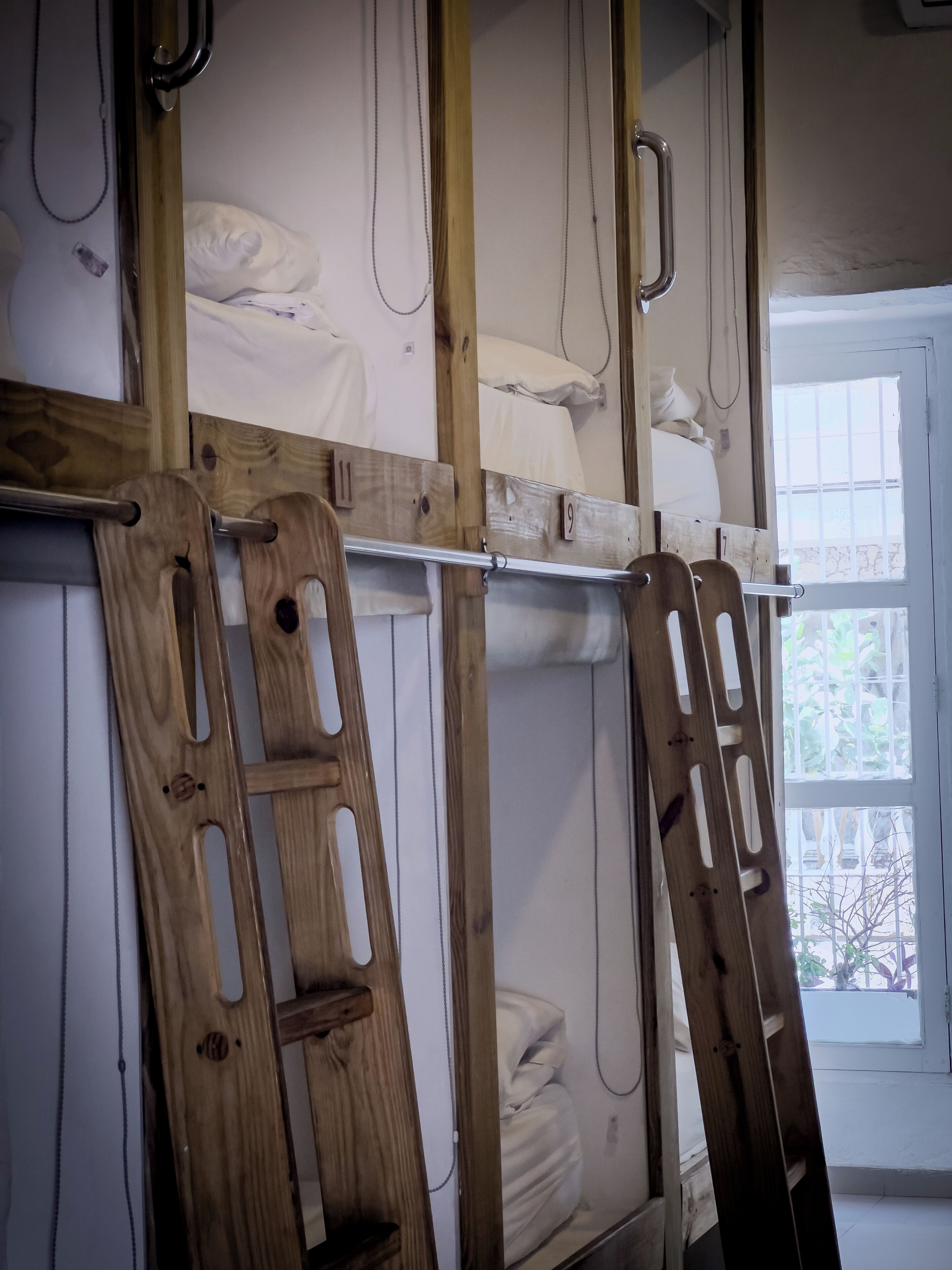 Un lit superposé avec des barreaux en bois et une fenêtre donnant sur un paysage verdoyant.