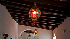 Un couloir orné d’un lampadaire décoratif, un escalier et une porte surmontée d’une grille en métal.