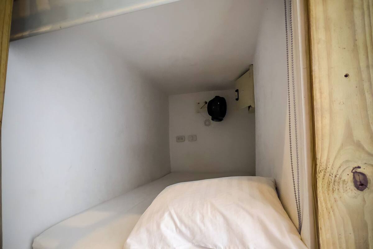 Ein kleines, geschlossenes Etagenbett mit einer einzelnen weißen Matratze und einem Kopfkissen.