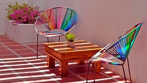 Une terrasse avec deux chaises colorées, une table en bois et un pot de fleurs.