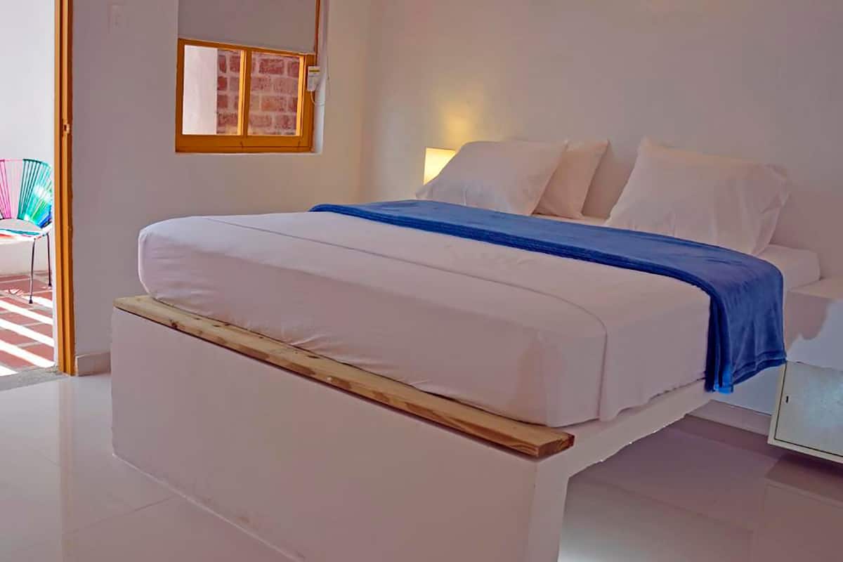 Ein Schlafzimmer mit Bett, Nachttisch, Fenster und Stuhl.