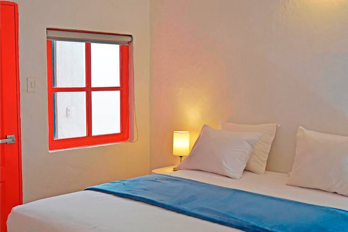 Ein Bett mit weißer Bettwäsche, einer blauen Decke und einem Nachttisch mit einer Lampe.