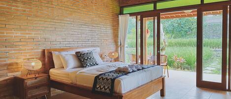Un dormitorio con pared de ladrillo, techo de madera y un ventanal con vistas a la vegetación.