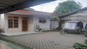 A house with a tiled driveway, a motorcycle, and a tricycle. - Hotel O Kamboja Homestay Syariah (Medan)