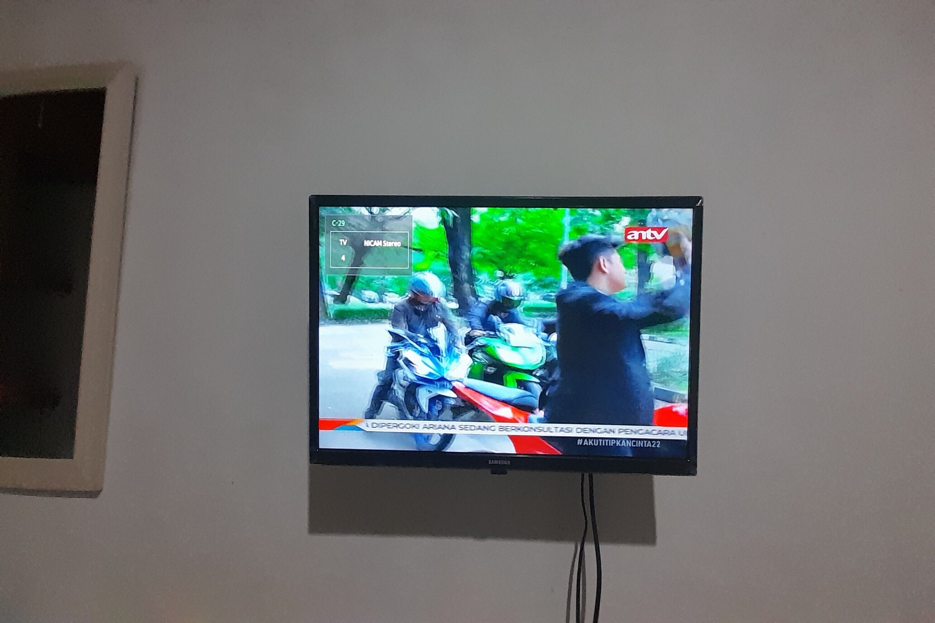 Ein an der Wand montierter Fernseher zeigt eine Nachrichtensendung.