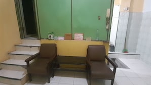 A reception area with two brown chairs, a small table, and a green door. - Hotel O Kamboja Homestay Syariah (Medan)