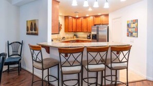 Une cuisine moderne avec des meubles en bois, un réfrigérateur en acier inoxydable et un coin bar avec des tabourets.