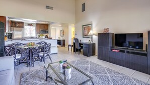 A spacious living area with a dining table, chairs, a coffee table, and a TV. - Palm Desert Condo w/ Patio & Golf Course Views! (Palm Desert)