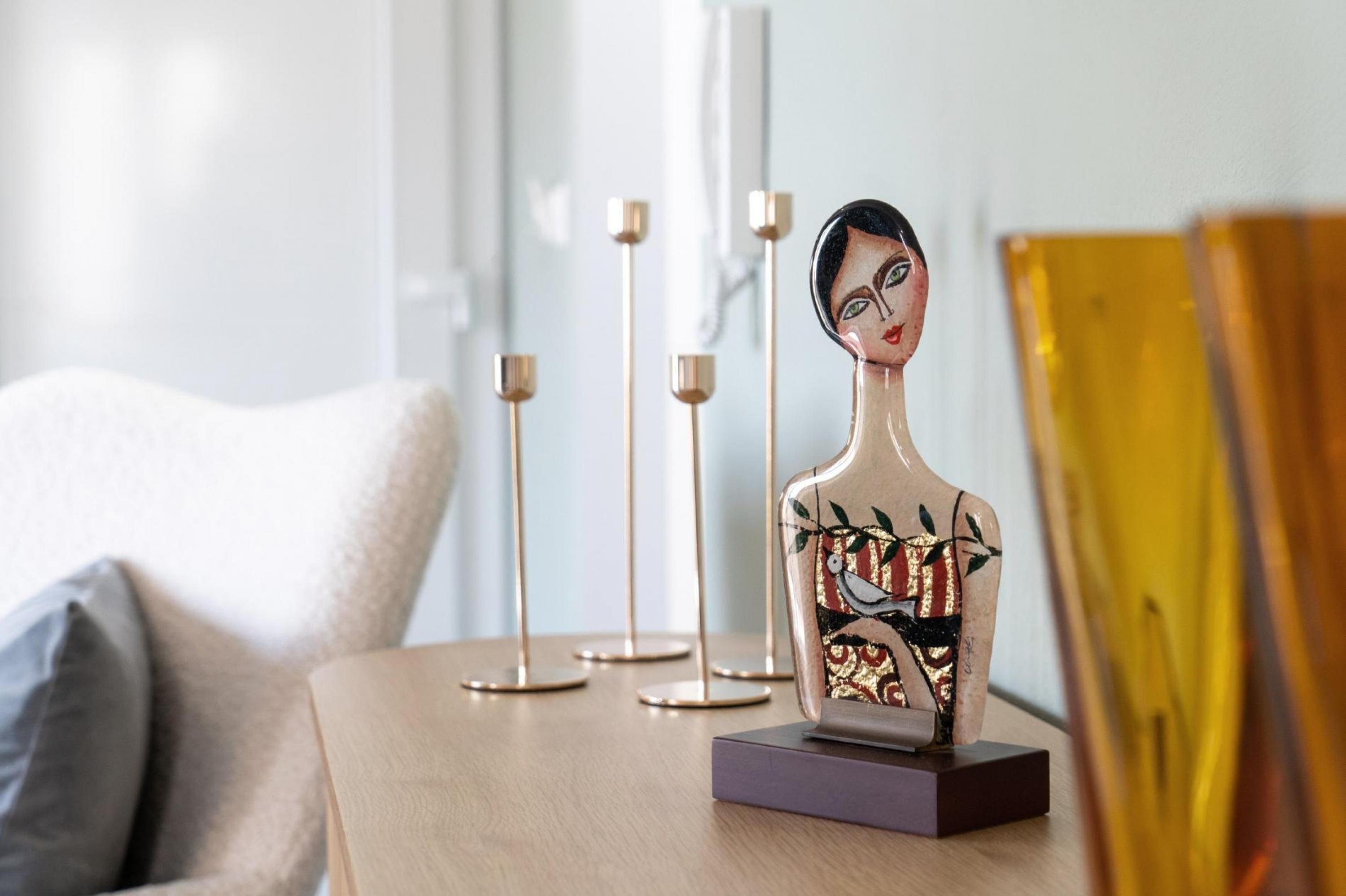 Een sculptuur op een tafel, met een lamp en een kussen op de achtergrond.