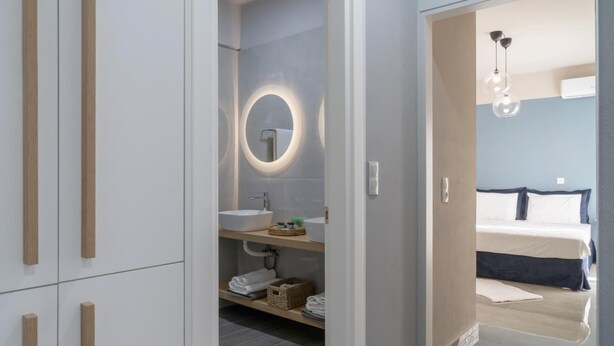 A modern bathroom with a round mirror, a sink, and a shower area. - Nisimos Modern Apartment (Hersonissos)