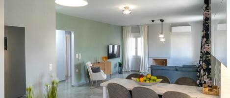 A modern kitchen with a dining area, a flat-screen TV, and a sofa.