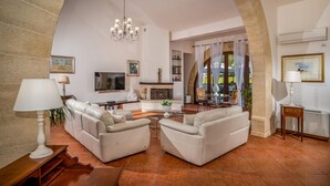A spacious living room with a fireplace, comfortable seating, and a television. - Villa Donna Agaver 6 Emma Villas (Paceco)