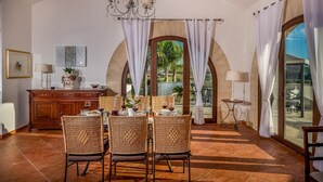 A dining area with wicker chairs, a wooden cabinet, and a table set for four. - Villa Donna Agaver 6 Emma Villas (Paceco)
