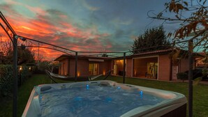 A hot tub in a backyard with a house and a hammock. - Villa Vivi 8 Emma Villas (Monte San Savino)