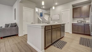 A modern kitchen with a central island, white cabinetry, and pendant lighting. - Top Flight (Colorado Springs)