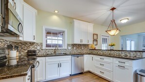 A kitchen with white cabinets, a granite countertop, a dishwasher, and a window. - Spacious Mooresville Home w/ Lake Norman View! (Mooresville)
