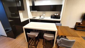 A compact kitchen with a central island, bar stools, and a microwave.