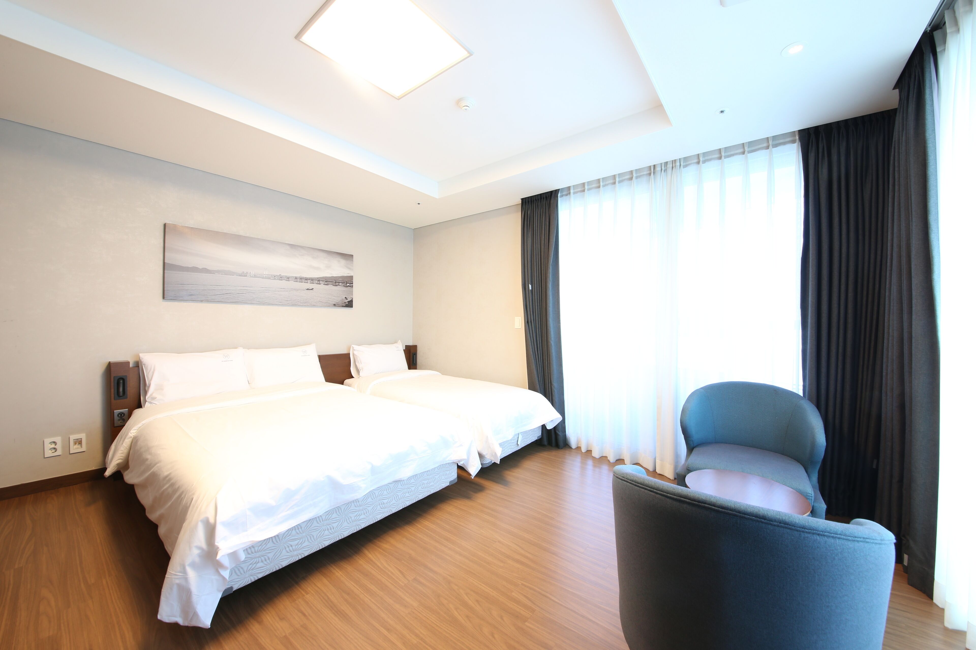 A hotel room with a large bed, a chair, and a painting on the wall.