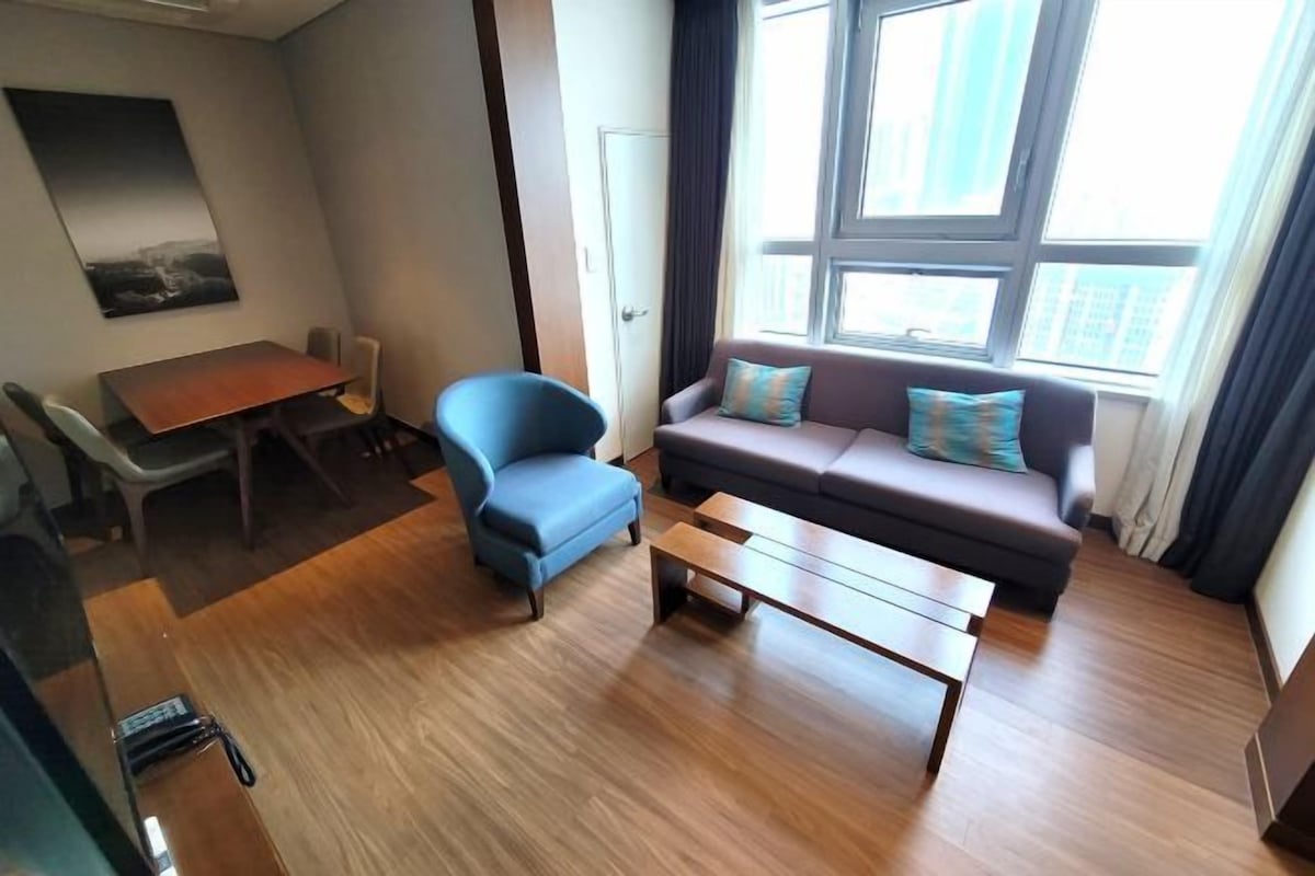 Una sala moderna con sofá, sillón, mesa de centro y mesa de comedor.