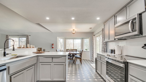 Une cuisine moderne avec des meubles blancs, un grand îlot central et un sol carrelé à motifs.