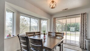Un coin repas avec une grande table en bois, six chaises et un vase rempli de fleurs.