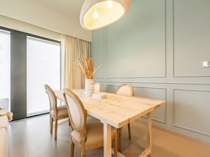 A dining area with a wooden table, four chairs, a vase with dried plants, and a large pendant light. - Lavishly Elegant 2BR with Breathtaking Burj View (Dubai)