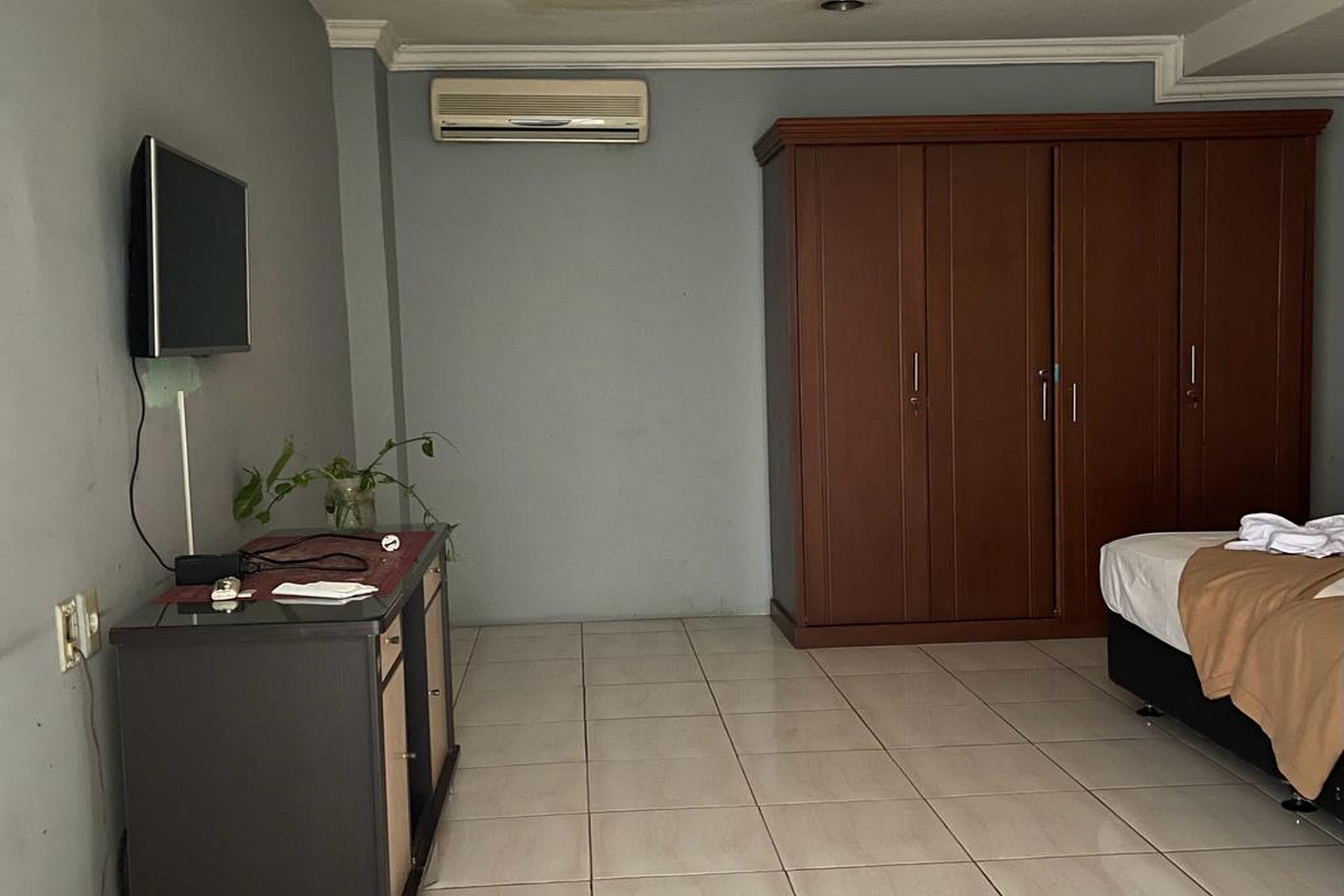 Una camera da letto con un letto, un armadio, una scrivania con un computer e una TV a parete.