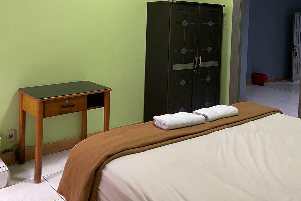Une pièce comprenant un lit, une table de chevet en bois, une armoire verte et une chaise rouge.