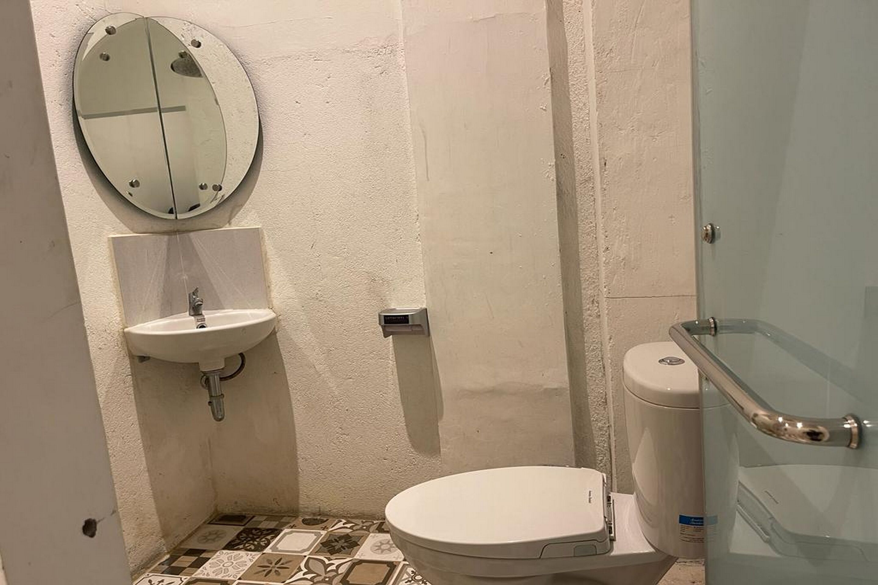 Un baño pequeño con inodoro, lavamanos y espejo.