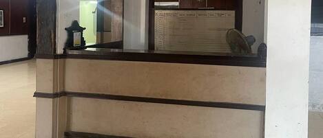 A reception desk with a counter, a wall-mounted fan, and a bulletin board.