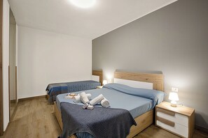 A bedroom with two beds, wooden headboards, a nightstand with a lamp, and a wooden floor. - Lake Maggiore View Terrace Over The Borromean Islands (Stresa)