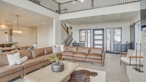 A spacious living area with a high ceiling, a leather sofa set, a wooden coffee table, and a staircase leading to an upper level. - Spacious Utah Escape w/ Balcony & Mountain Views! (Brian Head)