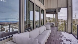 A modern outdoor deck with a sofa and chairs, large windows offering a view of a snowy landscape. - Spacious Utah Escape w/ Balcony & Mountain Views! (Brian Head)