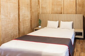 A hotel room with a wooden headboard, a bed with white bedding and a red trim, a small bedside table with a plant, and a nightstand. - Hotel O Bale Jiwan Mukti Narmada Near SMA NW NARMADA (Narmada)