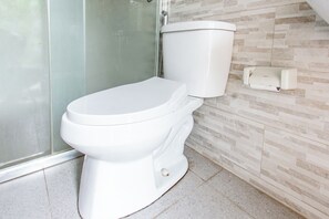 A modern bathroom with a white toilet, a glass shower enclosure, and a tiled wall. - Hotel O Bale Jiwan Mukti Narmada Near SMA NW NARMADA (Narmada)