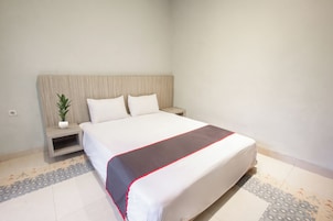 A hotel room with a large bed, a bedside table with a plant, and a patterned floor.